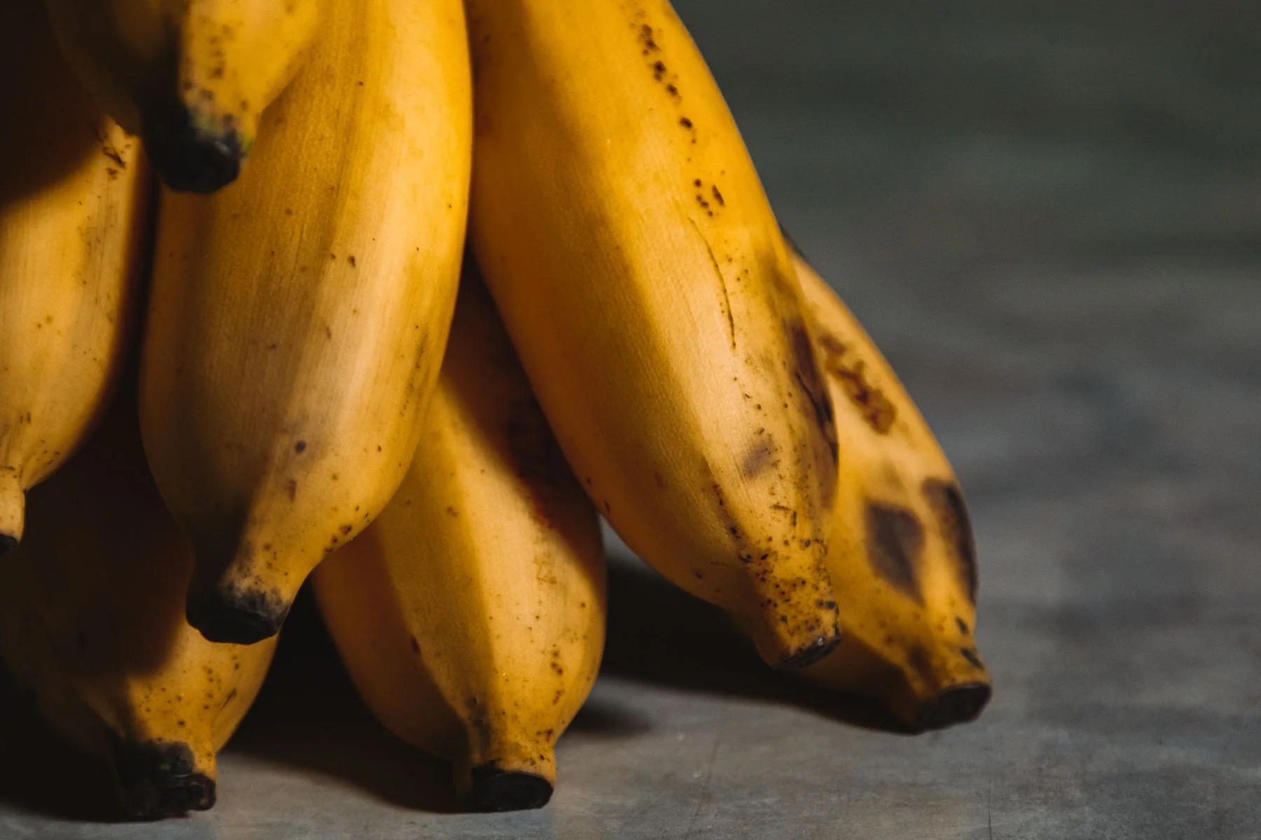 Zbliżenie żółtych bananów na ciemnej powierzchni.